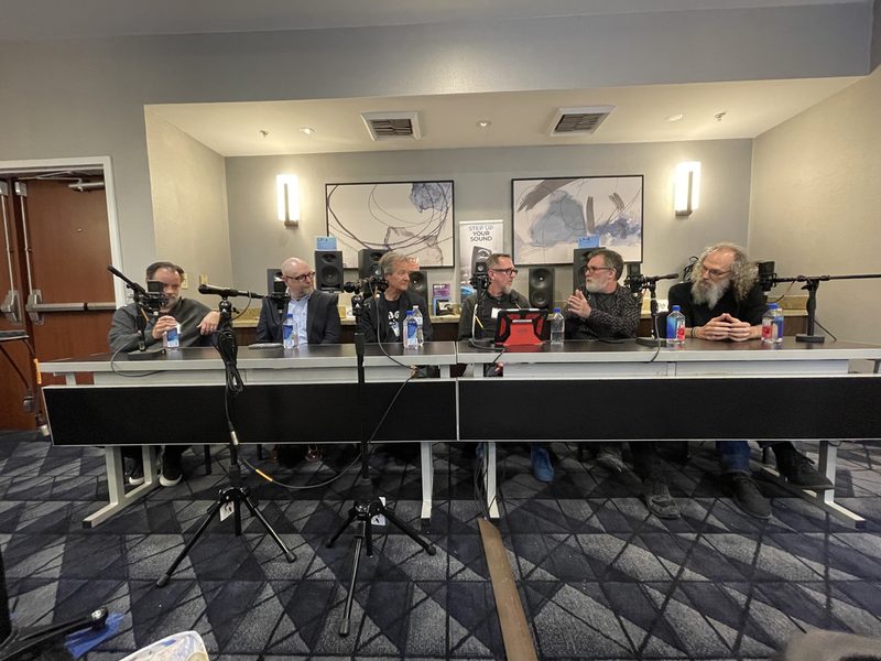 An Atmos panel at NAMM, six engineers seated at a table with microphones.